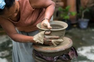 a woman molds pottery on a wheel