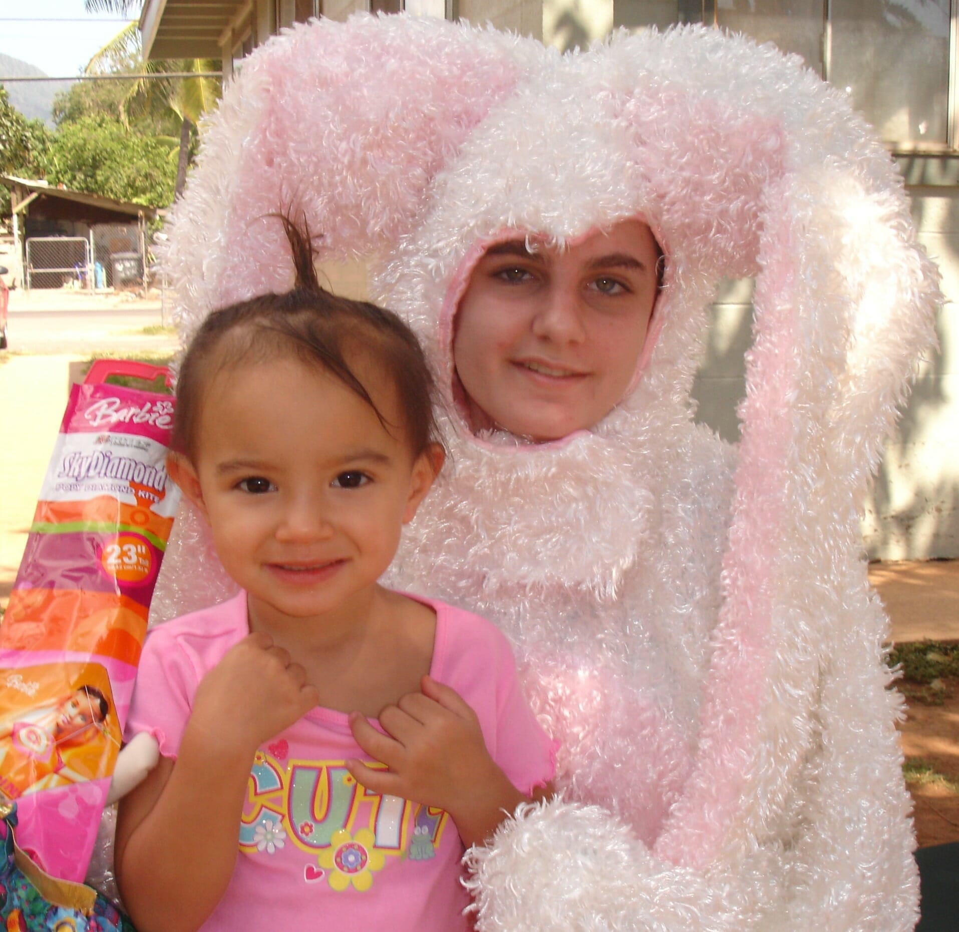 An adult dressed as the Easter bunny poses for a photo with a young girl