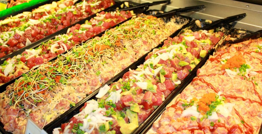 Dishes of poke are displayed in a deli.